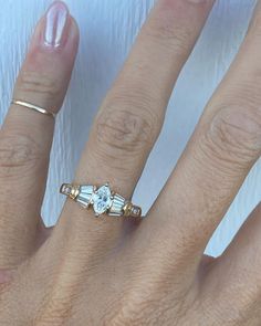 a woman's hand with three different rings on her left and the middle finger