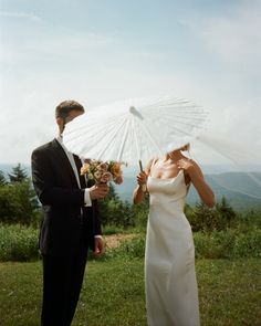 the bride and groom are holding an umbrella over their heads as they look at each other