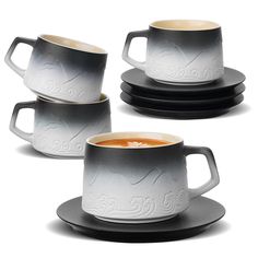 three cups and saucers with designs on them, one is black and the other is white