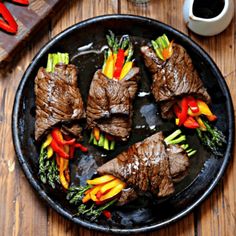 steak with peppers and asparagus on a black plate next to a cup of coffee