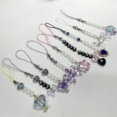 a bunch of necklaces that are sitting on a white table with beads and charms