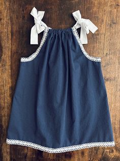 "Classic and timeless are these Swiss dot, all Cotton pillowcase dresses. Small white dots and cotton lace trim adorns this Navy blue Summer staple.  Designed to be tea length, these dresses have adjustable straps and can be worn through the years and grow with your child. Simply adjust the shoulder straps that tie into a bow or knot of your choice.  Hemline and armholes have a beautiful serged finish. These breathable and airy dresses can be worn alone in the Summer or during the cooler months, over a fitted top and leggings.  Hand wash, or machine wash delicate cycle. Lay flat to dry, press on medium heat. 100% Cotton.  Dress length is measured from center neckline to hemline. All sizes are approximately 20\" wide when laid flat and measured from side to side.  Size Chart 6-12 Months 15. Cute Polka Dot Cotton Dress, Sleeveless Cotton Sundress With Lace Trim, Cute Cotton Sundress With Adjustable Straps, Cute Cotton Broderie Anglaise Dresses, Cute Cotton Dress With Broderie Anglaise, Cute Sleeveless Sundress With Lace Trim, Cute Cotton Sundress With Spaghetti Straps, Sleeveless Polka Dot Dress With Lace Trim, Cotton Sundress With Lace Trim