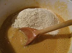 a wooden spoon in a white bowl filled with flour and other ingredients for the recipe