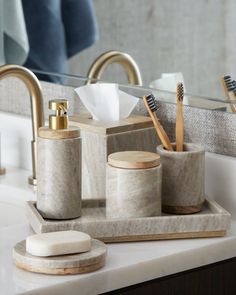 a bathroom counter with soap, toothbrushes and other items on it in front of a mirror