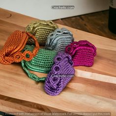 four crocheted purses sitting on top of a wooden table