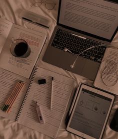 an open laptop computer sitting on top of a desk next to a notebook and pen