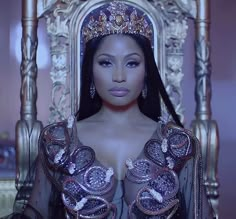 a woman wearing a tiara sitting on a chair in front of a gold throne