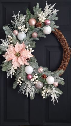 a christmas wreath with pink and white ornaments hanging on the front door's black door