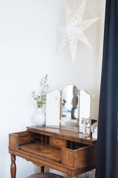 a wooden desk with a mirror, stool and star decoration on the wall above it