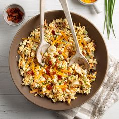 a bowl filled with rice and vegetables next to two spoons on top of a table