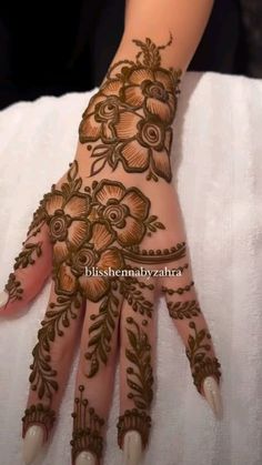 a woman's hand decorated with henna and flowers on her hands, showing the intricate