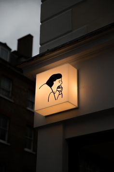 a lit up sign on the side of a building with a woman's face