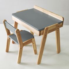 a small wooden table and chair set with grey seat pad on the bottom one side