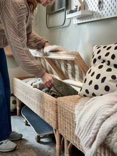 a woman standing next to a wicker bench with a cat on it's back