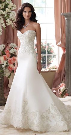 a woman in a white wedding dress standing next to a vase with flowers on it