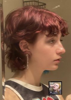 a woman with red hair is looking at herself in the mirror