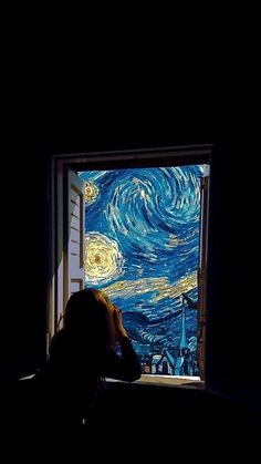 a person sitting in front of a window with the starry night painting on it