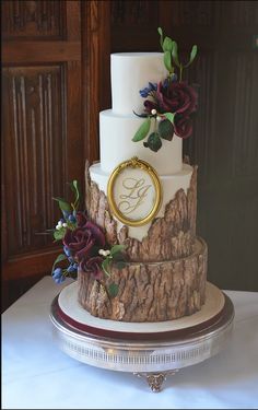 a three tiered wedding cake with flowers on the top and initials on the side