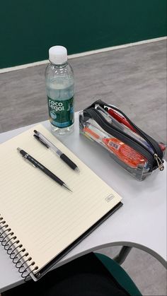 a notebook, pen and water bottle sitting on a table