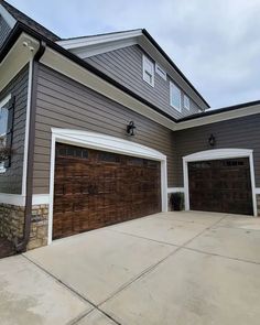 a house with two garages in the front and one on the other side that has brown siding