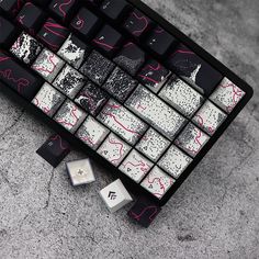 a computer keyboard sitting on top of a cement floor next to dices and buttons