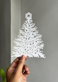 a hand holding up a cutout of a christmas tree