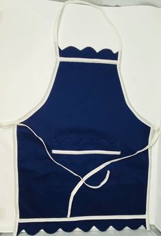 a blue apron with white piping on the front and side, hanging from a wall