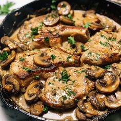 a skillet filled with chicken, mushrooms and gravy on top of a table