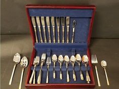 an assortment of silverware in a red case with blue linings and spoons