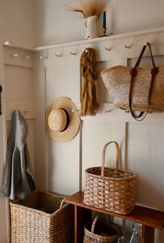 baskets and hats are hanging on the wall next to a coat rack in a room