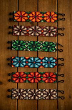 four bracelets with different colors and designs on wooden table next to eachother