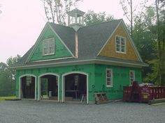 a large green building with two garages and a clock tower on it's roof