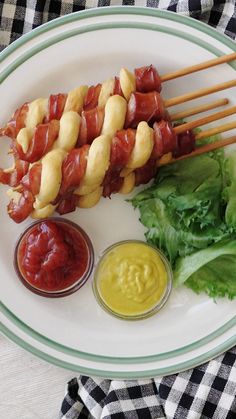 a plate with kebabs, lettuce and mustard on it