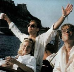 a man and two women on a boat waving to the sky with their arms in the air