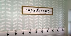 there is a sign on the wall that says mudroom and some hooks are hanging up