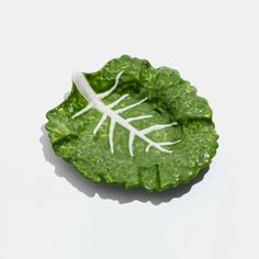 a green leaf shaped dish with white stems