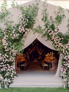 an outdoor wedding ceremony with flowers and greenery on the arch, decorated with candles