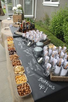 a long table covered with lots of food and drinks on top of a sidewalk next to a house