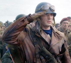 a group of men standing next to each other with helmets on their heads and one man holding his head