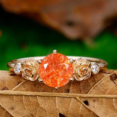 an orange diamond ring sitting on top of a leaf