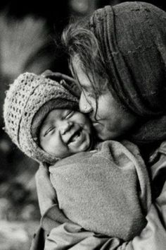 black and white photograph of a woman holding a baby in her arms, smiling at each other