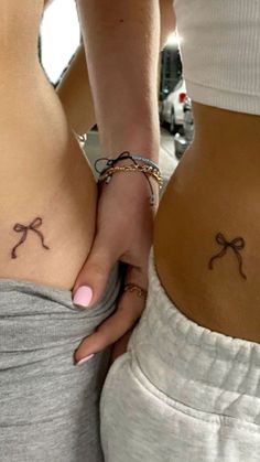 two women with matching tattoos on their stomachs