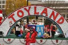 people are walking on the street in front of a sign that says toyland and is decorated with christmas decorations