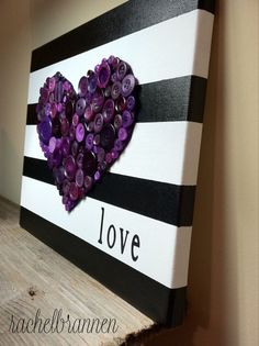 a black and white striped canvas with purple buttons in the shape of a heart that says love