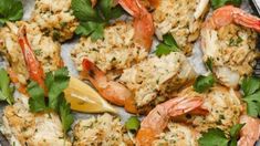 some shrimp and other food items are on a plate with garnishes, lemon wedges and cilantro