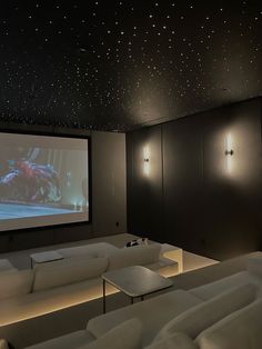 a large white couch in front of a projector screen with stars on the ceiling