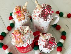 three mugs filled with hot chocolate and decorated cookies