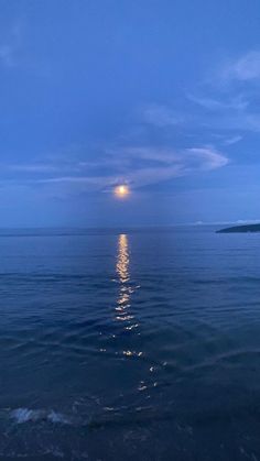 the moon shines brightly over the ocean as it reflects in the water's surface