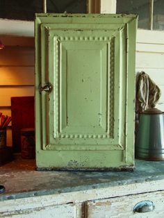 an old green door sitting on top of a wooden dresser next to a metal pot