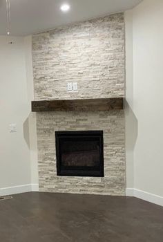 an empty living room with a fireplace in the middle and no one around it on the other side